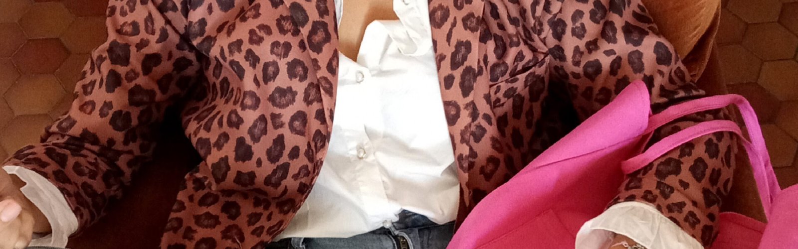 Tenue jeans clair blazer léopard et sac rose sur fauteuil velours marron